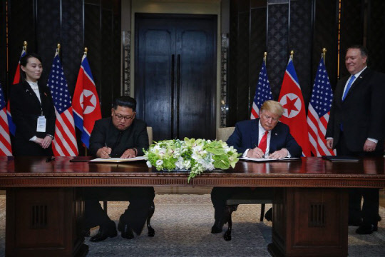 도널드 트럼프 미 대통령과 김정은 북한 국무위원장이 12일(현지시간) 싱가포르 센토사 섬 카펠라호텔에서 '6·12 싱가포르 공동합의문'에 서명하고 있다. 마이크 폼페이오 미 국무장관(오른쪽)과 김여정 북한 노동당 제1부부장이 옆에서 이를 지켜보고 있다.  연합뉴스